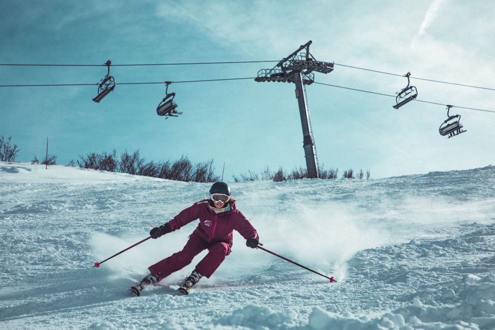 Jeune femme faisant du ski sur une montagne enneigée, devant les téléphériques.